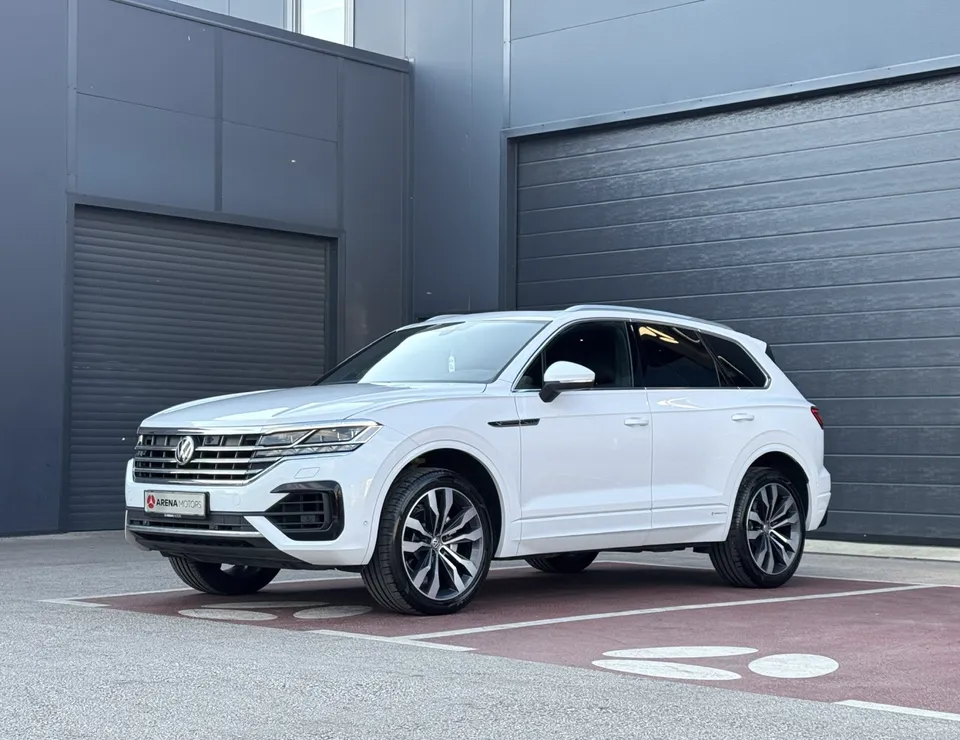 Bijeli Volkswagen Touareg R-line, prednji lijevi ugao, parkiran ispred sivih garažnih vrata