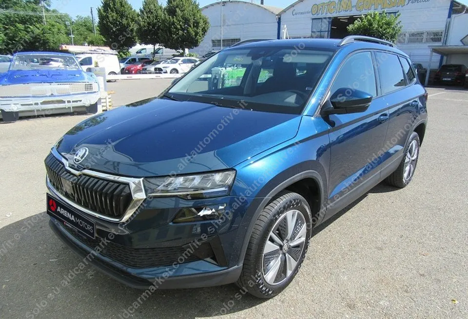 Škoda Karoq u plavoj boji, pogled sprijeda s lijeve strane, parkirana na asfaltu ispred hale