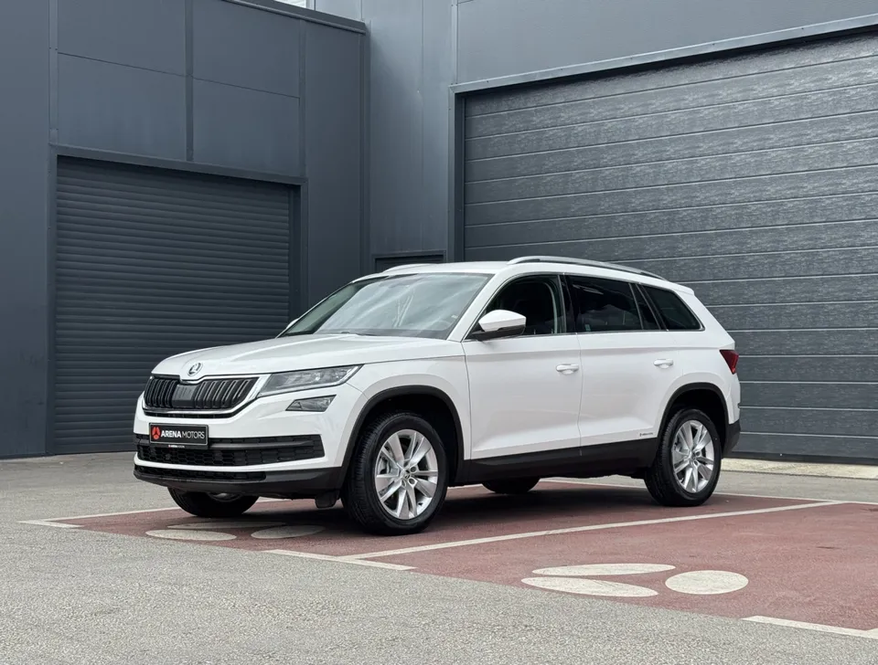 Bijela Škoda Kodiaq, pogled sprijeda sa strane, ispred sivog objekta salona