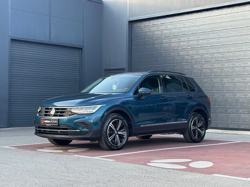Volkswagen Tiguan u plavoj boji, prednji lijevi ugao, parkiran ispred sive hale