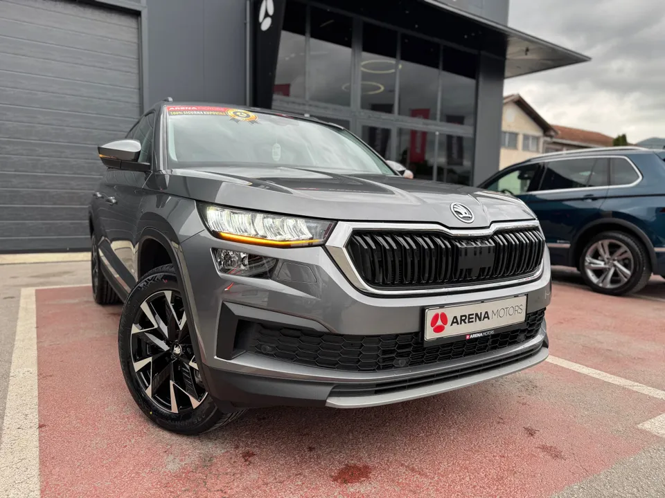 Siva Škoda Kodiaq, prednji desni ugao ispred staklene fasade salona