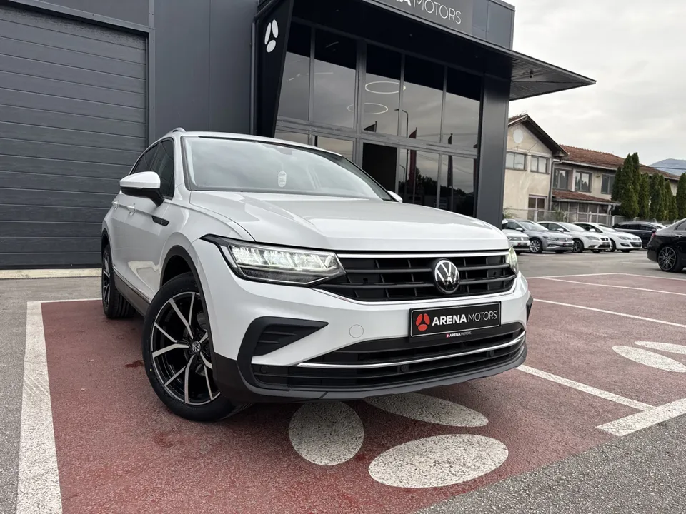 Bijeli Volkswagen Tiguan, prednji desni ugao ispred zgrade salona