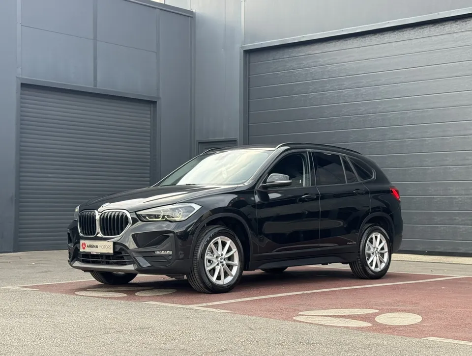 BMW X1 crne boje, prednji lijevi bočni pogled, ispred sive garažne rolo-vrata