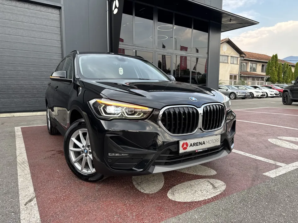 BMW X1 crne boje, prednji desni ugao ispred staklene fasade salona