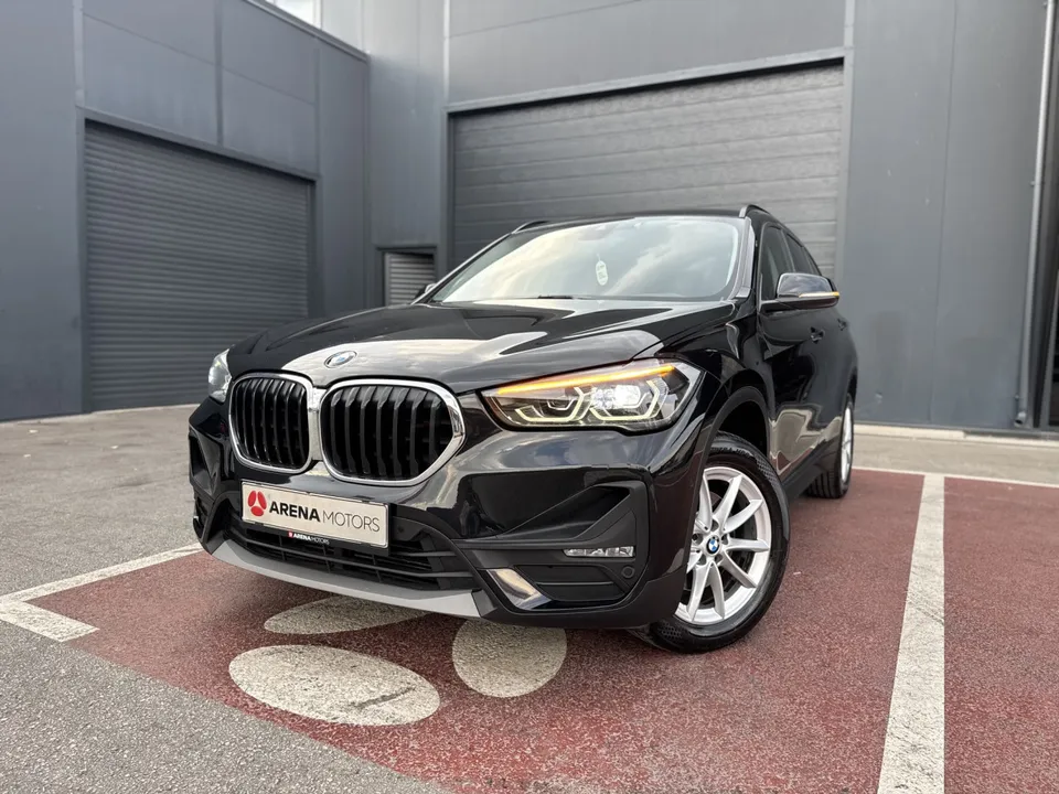 BMW X1 crne boje, prednji lijevi ugao s LED farovima i alu felgom na parkingu