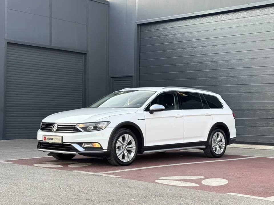 Bijeli Volkswagen Passat Alltrack, prednji lijevi ugao, parkiran ispred sive hale