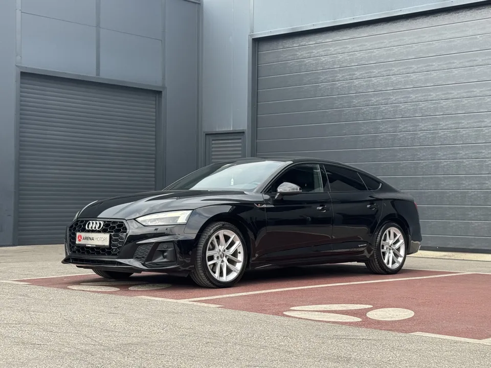 Crni Audi A5 Sportback, pogled sprijeda sa strane, ispred sive hale