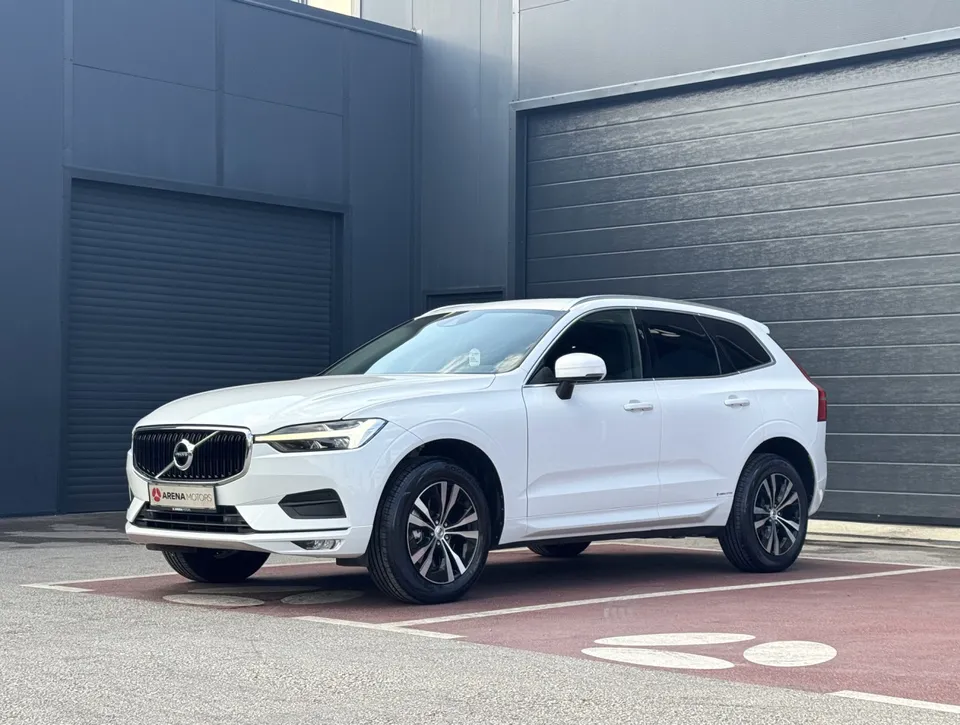 Bijeli Volvo XC 60, prednji lijevi bočni pogled, ispred sivog objekta