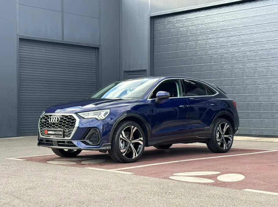 Audi Q3 Sportback plave boje, prednji lijevi ugao, 20" alu felge, parkiran ispred sive hale