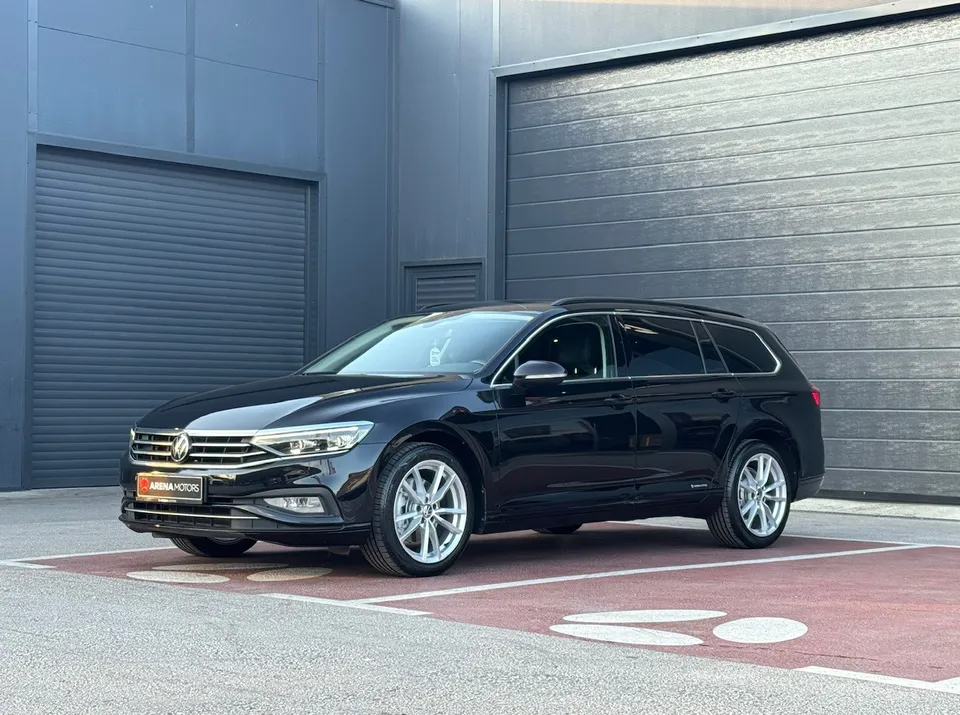 Crni Volkswagen Passat Variant, bočni pogled sprijeda ispred sivih garažnih vrata, aluminijske felge