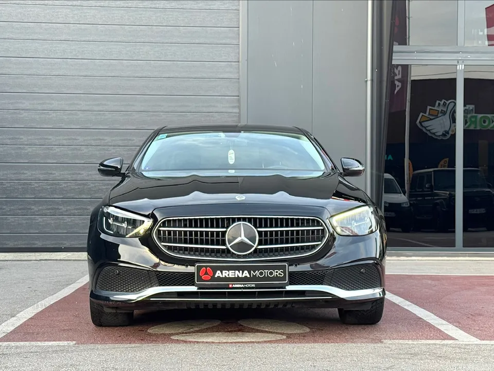 Crni Mercedes-Benz E 220 d snimljen direktno sprijeda, maska, farovi i prednji branik