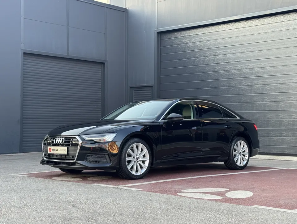 Audi A6 limuzina, crna, prednji lijevi bočni pogled na parkingu ispred sivog objekta