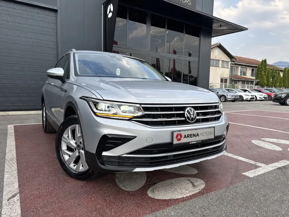 Volkswagen Tiguan, prednji desni ugao s alu felgom ispred staklene zgrade salona