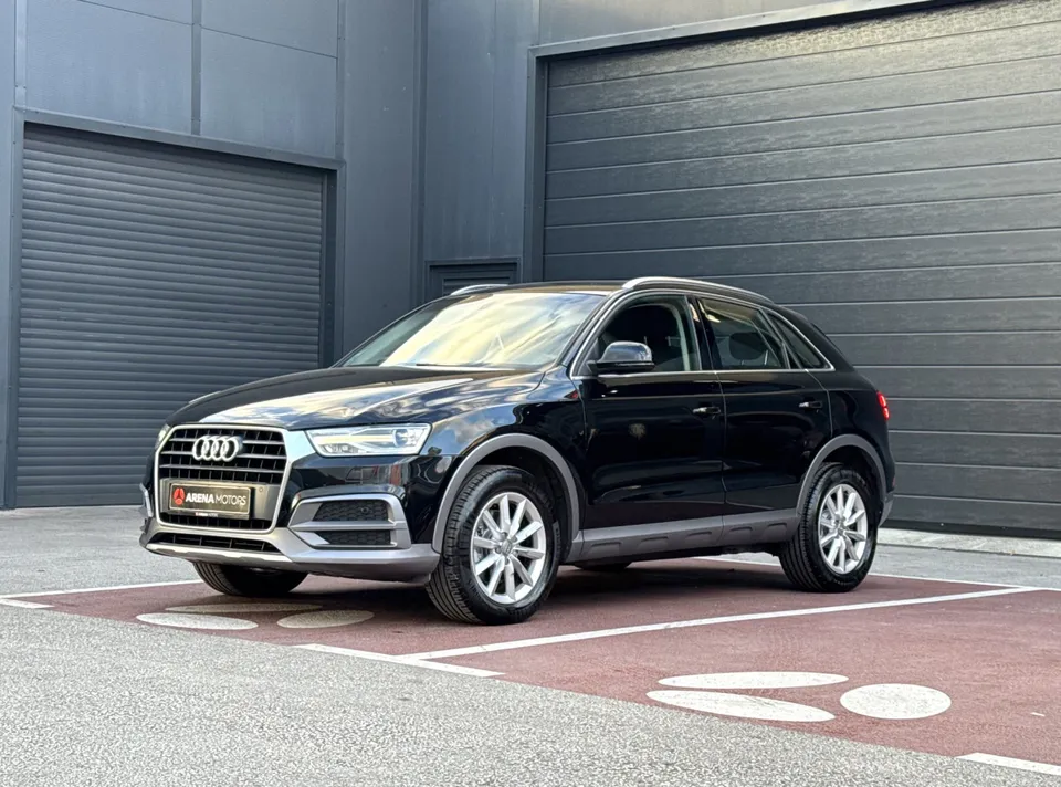 Audi Q3 crne boje, pogled sprijeda i sa lijeve strane ispred sive garaže