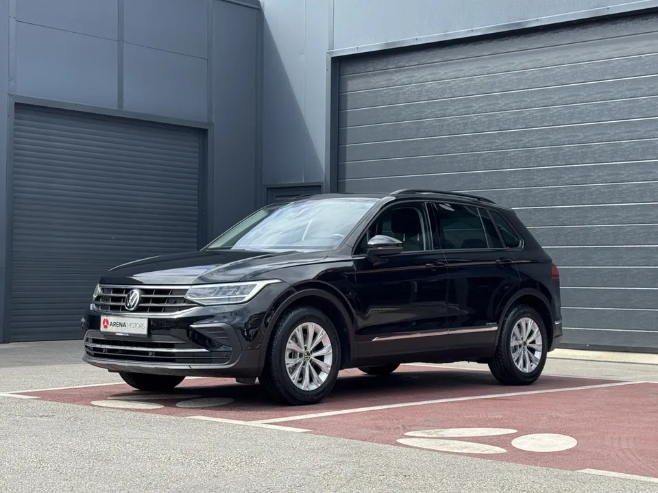 Crni Volkswagen Tiguan, prednji lijevi ugao, parkiran ispred sivih garažnih vrata