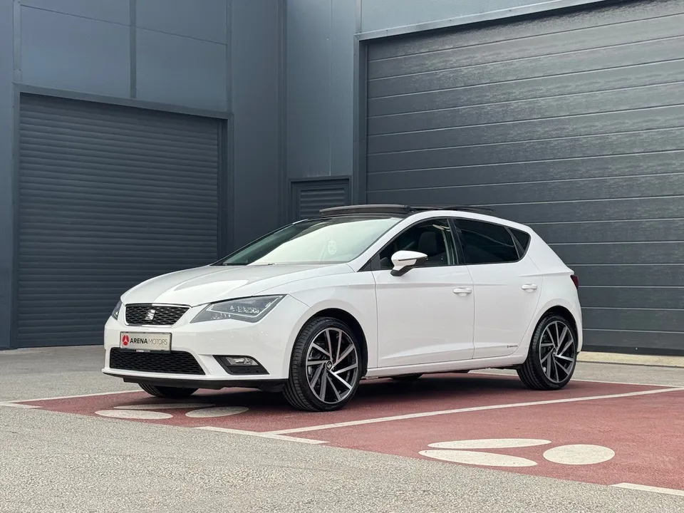 Bijeli Seat Leon, prednji lijevi ugao, alu felge i panoramski krov ispred sive hale