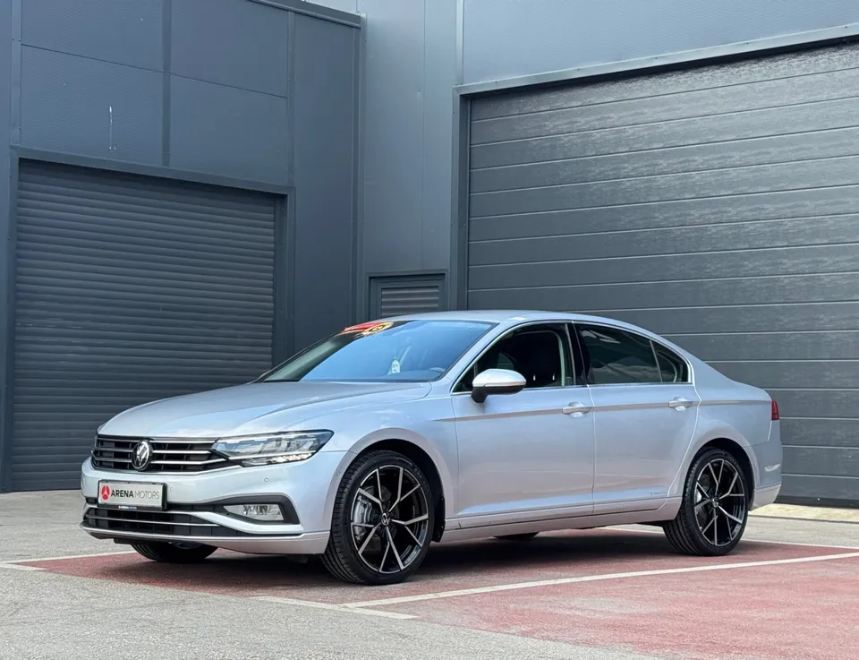 Volkswagen Passat limuzina srednje sive boje, prednji lijevi ugao, crne alu felge, ispred sive hale