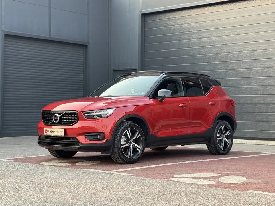 Volvo XC 40 R-Design, crvena boja, prednji lijevi bočni ugao, crni krov i alu felge ispred sive garaže